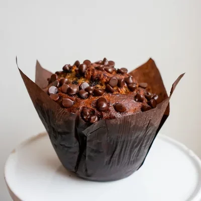 A banana muffin with chocolate chips mixed throughout the batter, and sprinkled with more chocolate chips on top!